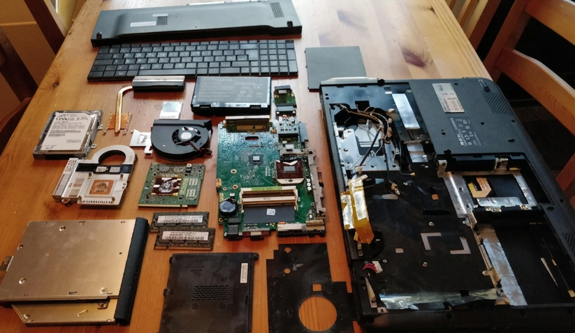 Disassembled laptop hardware components laid out on a wooden table